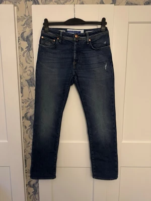 Jacob Cohën - Storlek: Midja 38, Grenhöjd 26, Lårvidd 28,5, Innerbenslängd 73, Benöppning 18 (cm). Fabriksdistresserade jeans med perfekt passform. Passar ca 170–180 cm, 70–85 kg. I utmärkt skick med hög kvalitet och tidlös stil från Jacob Cohen.