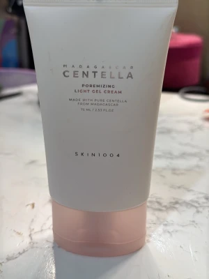 Centella Poremizing Gel Cream - Lätt gelkräm från SKIN1004 med centella från Madagaskar. Tuben är vit med en ljusrosa botten och rymmer 75 ml. Perfekt för dig som vill ha en återfuktande och lugnande ansiktskräm med fräsch känsla.