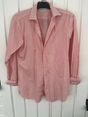 randig skjorta John Henric - Säljer en klassisk skjorta från John Henric med ränder. Skjortan har lång ärm, krage och knäppning framtill. Tillverkad i mjuk bomull som känns skön mot huden. Perfekt för en clean och stilren look.