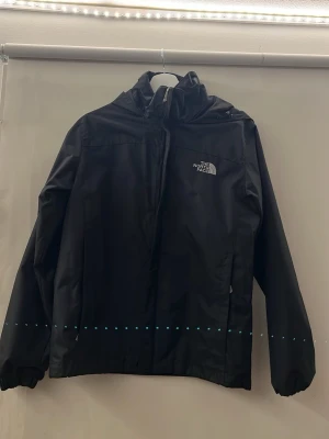 Svart vindjacka från The North Face - Säljer min svarta vattentäta vindjacka ifrån the North face, jackan är använd ett fåtal gånger men ser ut som ny i skicket, har inga skador/slitage eller liknande, jackan är i storlek M och passar dig som är från 165-175cm ungefär. 