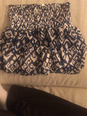 Kort blåvit mönstrad klänning - Supersöt kort klänning med blåvitt mönster och volang. Klänningen har smock upptill och ett luftigt, flowy tyg som ger en avslappnad vibe. Perfekt för varma dagar eller när du vill sticka ut lite extra.