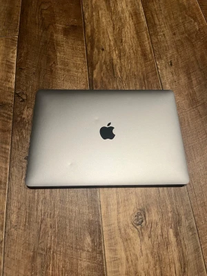 MacBook i silver från Apple - Snygg och stilren MacBook i silver med klassisk Apple-logga på locket. Tunn och smidig design i aluminium, svart tangentbord och stor trackpad. Perfekt för plugget eller kreativa projekt.