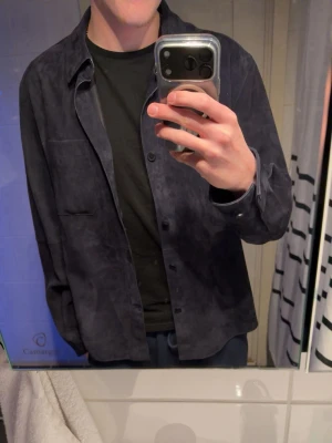 Mörkblå skinnjacka från Zara - Snygg mörkblå skinnjacka från Zara Leather Collection. I storlek M. Ny pris runt 1800kr jätte fint skick bara en knapp som sitter lite löst ”bild4” men går lätt o fixa om den skulle lossna nån gång då de finns 2 nya knappar i jackan 