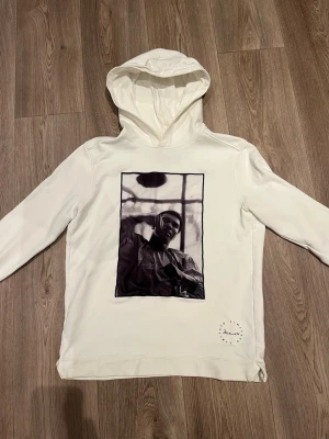 Limitato Hoodie  - Säljer en stilren vit hoodie från Limitato med ett stort svartvitt fototryck av Muhammed Ali på framsidan. Hoodien har huva och en rund logotyp med signatur på nedre delen. Tröjan är i storlek M!