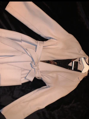 Beige kappa med bälte Massimo Dutti  - Oanvänd/ beige kappa från Massimo Dutti.  Perfekt för dig som gillar en enkel men elegant look. Storlek S men lite stor i storleken