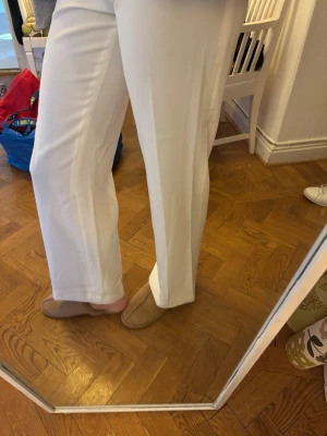 Vita raka kostymbyxor - Säljer ett par stilrena vita kostymbyxor med rak passform. Byxorna har hög midja och är tillverkade i ett mjukt, bekvämt material som ger en snygg siluett. Jag är 179 och tycker de är för korta, passar någon som är kortare en ca 170. 