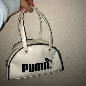 Puma handväska - En vit Puma handväska som inte kommer till användning. Väskan har ett stort utrymme i och håller din struktur. Handväskan är även lätt att torka av för att vara vit. Älskar denna väskan dock använder jag den för lite för att ha kvar. Köptes ny för 450 kr.