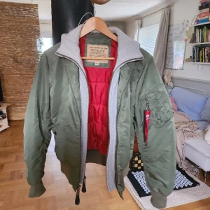 Bomberjacka (Alpha Industries) - Storlek small. Toppenskick! Knappt använd. Nypris runt 2500kr. Bortagbar luva (hela gråa delen av jackan).