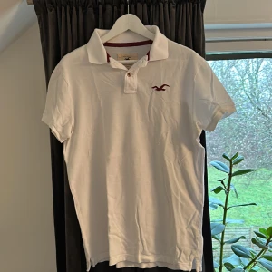 Piké vit Hollister M - Vit piké från Hollister. Sparsamt använd. Inga gula ringar. Stl M