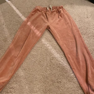 Rosa mjukisbyxor❤️ - Rosa mjukisbyxor med mudd längst ner vid bena💕 Deg är guldiga band vid midjan🫶🏻 Banden är lite slitna men det kan man klippa till😽Finns en matchande jacka till om ni går in på min profil❤️