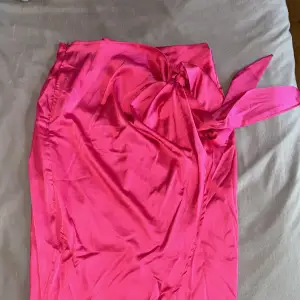 En omlott kjol med en knytning där du kan knyta en rosett själv. Super fin och somrig i färgen!