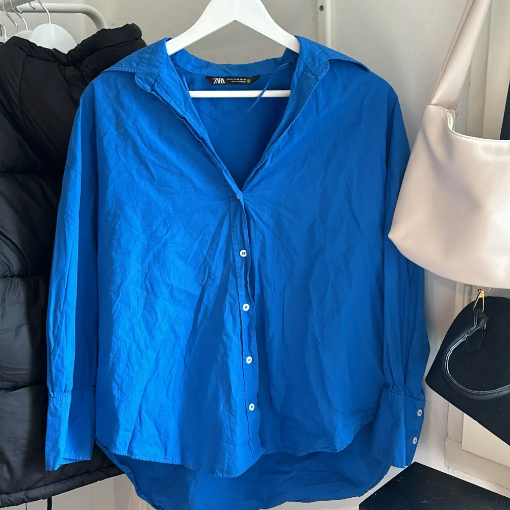 Blå skjorta från Zara i storlek xs. Väldigt fin till sommaren, går att öppna till en kofta. Det finns knappar längs ut vid armarna som också går att öppna. Har använts en gång (nyskick). Passar dig som är mellan xs-m (100% bomull) . Skjortor.