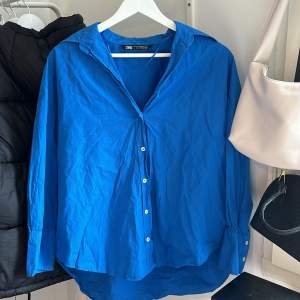 Blå skjorta från Zara i storlek xs. Väldigt fin till sommaren, går att öppna till en kofta. Det finns knappar längs ut vid armarna som också går att öppna. Har använts en gång (nyskick). Passar dig som är mellan xs-m (100% bomull) 