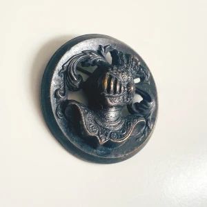 Brosch  - En rund brosch med hjälmbeklädd riddare  Okänd metall 