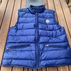 Moncler gui väst - Säljer min Moncler gui väst, äkta Storlek 3, motsvarar S/M Skick: 8/10 Liten lagning på ryggen men ej inget man tänker på eller som syns mycket!  