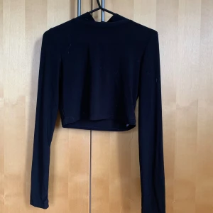 Svart magtröja - Svart magtröja med turtleneck. Materialet är Polyester. Rebecca Stella’s klädmärke.