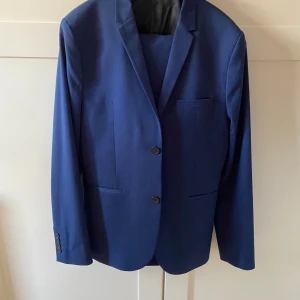 Blå kostym - Blå kostym från H&M i storlek 50. Nypris på denna modell ligger på över 1000kr, runt 1300kr. Har använts 2-3 gånger men säljer för att den har växt ut. Perfekt till val eller studenten!
