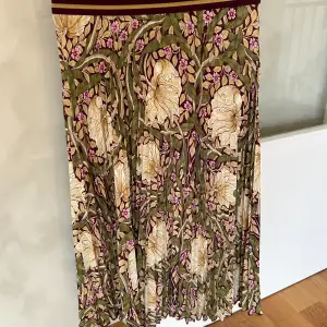 Plisserad kjol från H&M:s Morris & Co-kollektion. 100 % polyester.