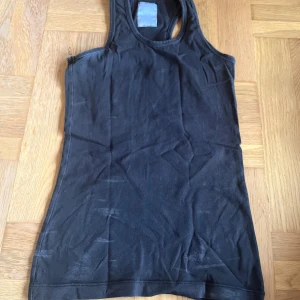 Linne  - Svart träningslinne men glittrig text på ryggen där det står gymnast. 