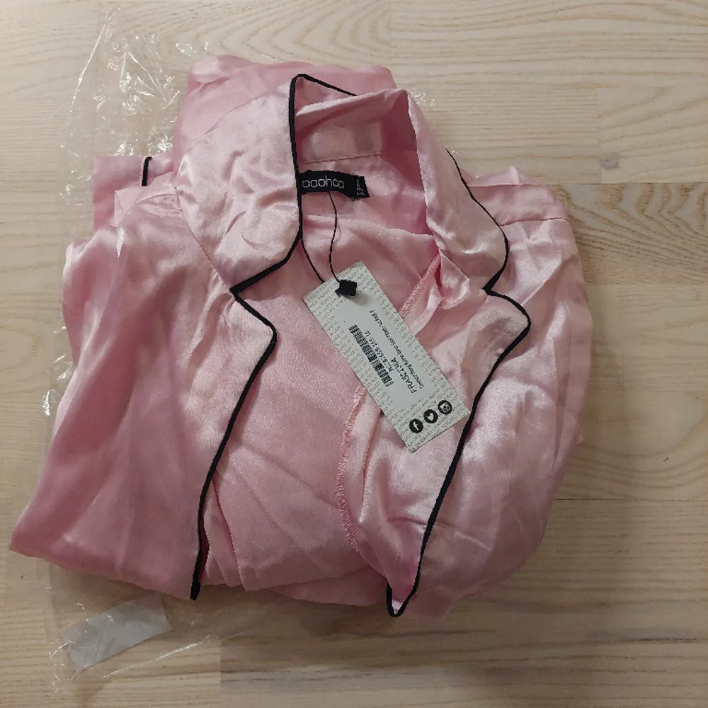 Långärmad skjorta och byxor i rosa satin från Boohoo med svarta kantband.  Endast testat men passade tyvärr inte, så nytt med lapparna på.  Strl EU 34/US 4. Övrigt.