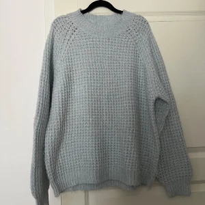 En ljusblå stickad tröja - Tröjan är i strl L men jag som S/M använde den som oversized. 