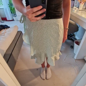 Grön volangkjol  - En söt grön blommig volangkjol som har rosettsknytnig på sidan från veromoda. Skulle säga att man kan ha den i st S-L då man kan justera storleken i midjan. Från veromoda.  Satt pris gäller. 🌸