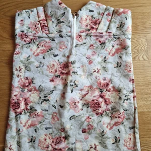 Blommig spetstopp med dragkedja - Passar mindre byst Jättefint material som är stretchigt Har en till i annat mönster Fin dragkedja 