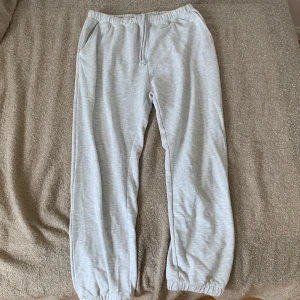 Ljusgrå mjukisbyxor från 157 - Ett par bekväma ljusgrå mjukisbyxor från märket 157. Byxorna har en elastisk midja med dragsko och elastiska muddar vid bensluten. Dem har fickor och är i storleken L men skulle säga M eftersom att man kan spänna åt dem i midjan.