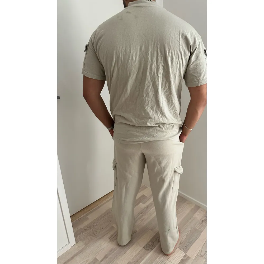 Set för herr med mjukisbyxor och en skön T-shirt. Både tröja och byxor har fickor på sidorna (se bild). För referens är han 185 cm. Fläckarna på bilderna har tvättats bort.. Farkut & Housut.