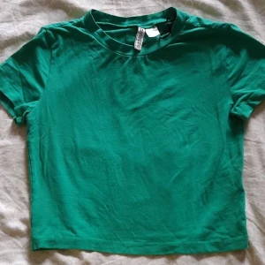 Grön t-shirt från H&M - En enkel och bekväm grön t-shirt från H&M Basic. T-shirten har korta ärmar och en rund halsringning. Köpt för ungefär 2 år sedan (men inte använt den särskilt mycket).  Storlek M.  