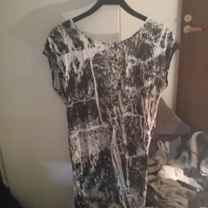 Ärmlös blus stl S - Ärmlös blus stl S i svart/vitt batikliknade mönster med dragkedjor på axlarna. Lång så den går ner wn bit på låren. Fint begagnat skick