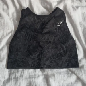 Gymshark sportbh  - Svart/grå mönstrad sportbh från gymshark. Korsad rygg. Strl. S. Knappt använd då den är för liten för mig. Vaddering på insidan som man kan ta ut. 