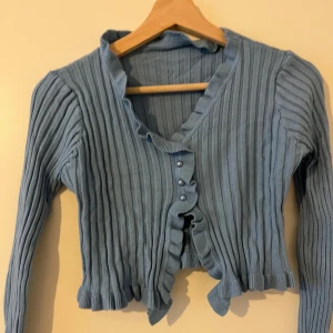Topp - Kort topp i blå med pärlknappar. Storlek M. Aldrig använd.