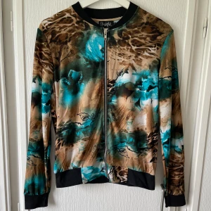 Fin kofta - Väldigt fin kofta i bruna färger blandat med turkos. Mönstret ser lite skogsaktikgt ut. Använd några fåtal gånger. I mycket bra skick. Bekväm. 