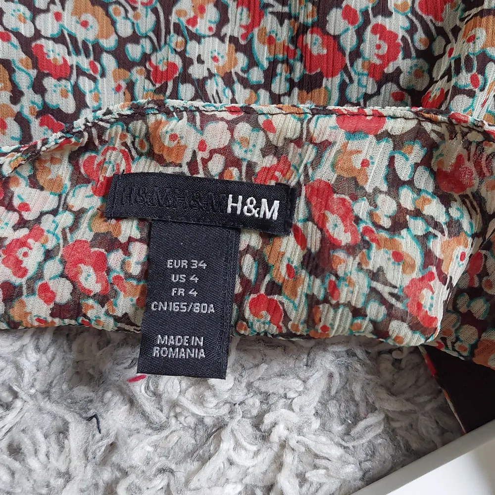 En blommig klänning från H&M i storlek XS. Klänningen har korta ärmar och en v-ringad hals. Justerbar storlke tackvare ett elastiskt midjeband och knytband i ryggen. Använd ca 1 gång och säljer då den är för liten för mig.. Klänningar.