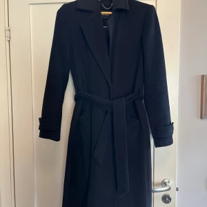 Yllekappa - Svart yllekappa, knappar, skärp, fickor. 