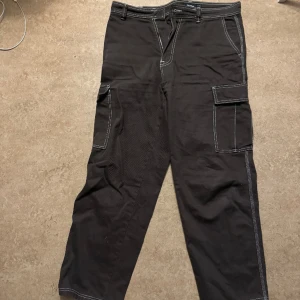 Bruna byxor med vita stygn - Byxan är max använd 3 gånger, knappen har åkt av men det går enkelt att sy på en ny