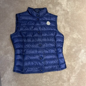 Moncler väst dam - Säljer denna snygga dam väst från Moncler. Nypris 7000! Inga defekter och därför är mitt pris 2999.  Kond 9/10, knappt använd. Färgen blå/lila