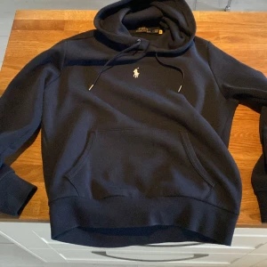 Ralph lauren hoodie  - Ralph lauren hoodie, marinblå  Köpt och nypris för 1999kr Använd ett fåtal gånger.  Finns inget fel på den, de ända är att i sidan vid midjan har den blivit nopprig men syns knappt. För mer frågor kontakta gärna.  *Pris går att diskutera*