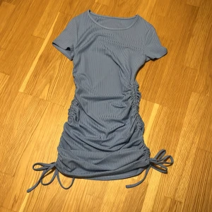 Blå tight klänning - Jättefin blå klänning! Man kan justera längden med hjälp av banden på sidan. Aldrig använd och är som ny 💗