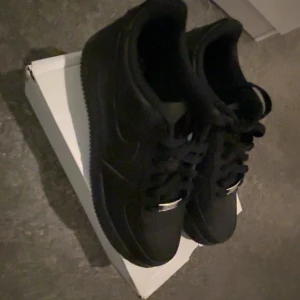 Air Force 1 Svart - Säljer ett par Air Force 1 i färgen svart. Jag säljer skorna för att jag ångrade mig att jag hade köpt de. Skorna är i gott skick, och knappt använda. Tveka inte att höra av dig vid intresse! Diskuterbart pris!