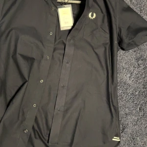 Fred Perry Skjorta  M/L - Tjena! Säljer min Fred Perry kort armad skjorta då jag insåg efter mitt köp att den satt lite tajt. Det är en M men ska passa L, alternativt gränsen till XL.  Vid frågor ställ dem gärna.  Snabb affär går jag ner i pris! 