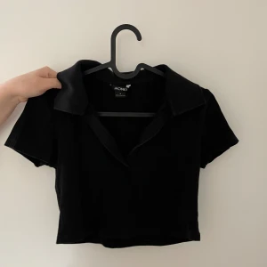 Svart topp - Svart ribbad croptop med piké-krage. Knappt använd och i mycket gott skick