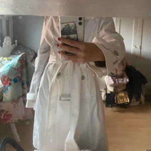 Vit kappa - Vit vår trench-coat, helt i nyskick. Snygga detaljer perfekt för våren. Står stri 44 i, men snygg oversized och sitter bra pả mig som brukar ha 36. Säljer pga att jag har en nästan exakt likadan Nypris: 1000 kr