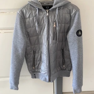 John Ricci cardigan - grå  - En John Ricci cardigan köpt i andrahand från annan här på plick. Finns tecken på användning av tröjan men inga skador/fläckar. Skick 8/10 Liten i storlek så passar även XS