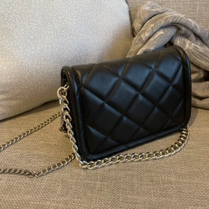 Handväska - Säljer denna handväska eftersom den inte kommer till användning längre. Nyskick och har endast använd ett fåtal gånger. Väskan har både lång och kort kedja. Hör av er vid några funderingar!💕