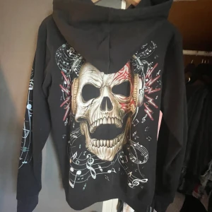 Zip up hoodie - Cool zip up hoodie med dödskalle bak och fram, ärmarna är med musik noter, aldrig använd 