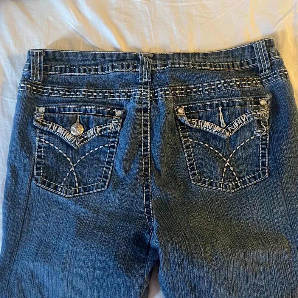 Supertrendiga jeans. Lågmidjade med häftiga fickor och kontrast-sömmar.  Väldigt häftiga, fin tvätt.    En Sten har lossnat på knappen på ena bakfickan  Storlek motsvarar 36-38. Jeans & Byxor.