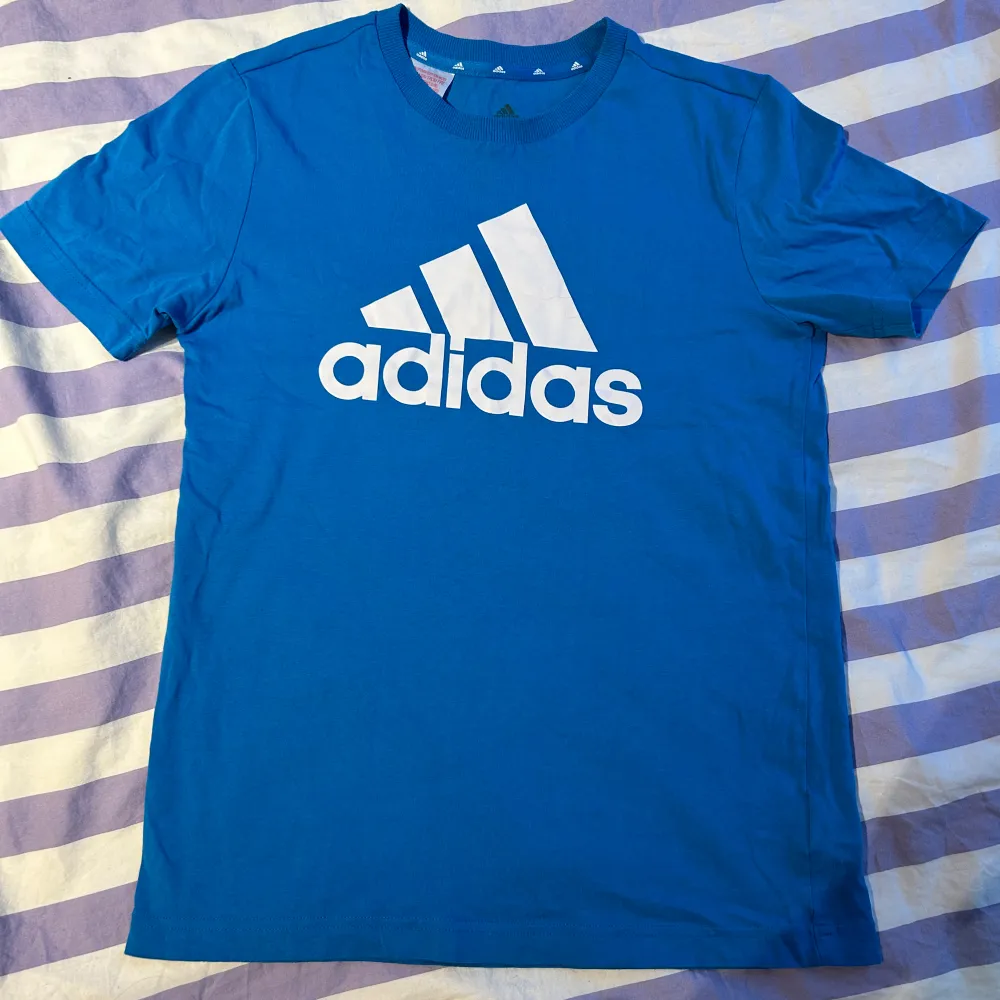 Säljer åt min bror då han växt ur. Blå adidias t-shirt i storlek 164, 13-14 år. I bra skick. Säljs för 75 kr.. T-shirts.
