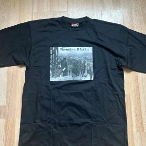 Empire State t-shirt - Ett egendesignat tryck på en fräsch secondhandtröja. Ett tryck från vår kollektion ”Noire et Blanche”. Vårt motiv ’Empire State’ är en svartvit bild tagen 1930 på en byggarbetare arbetandes på skyskrapan Empire State Buildinh, Manhattan - New York